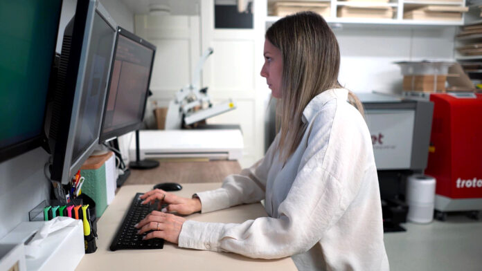 Das Bild zeigt eine Frau, eine Tastatur und einen Bildschirm